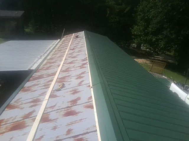 Old rusted panels beside newly installed green metal roofing — Wind Damage Roof Repair by Roofing Brothers in Lake Panasoffkee