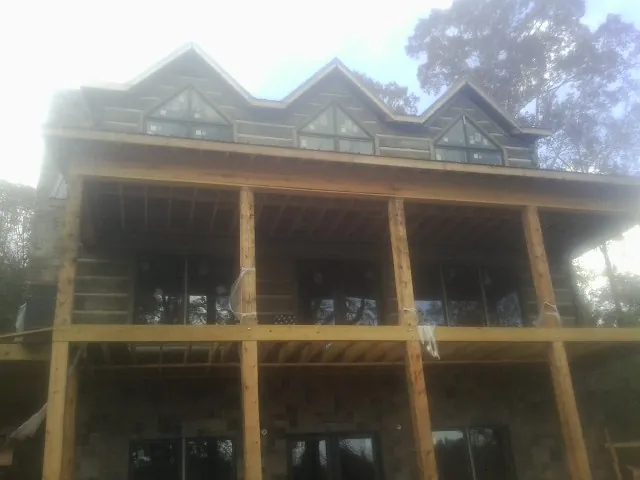Dormers and porch framing on a large log home under construction — Roof Coating work by our crew in Lake Panasoffkee