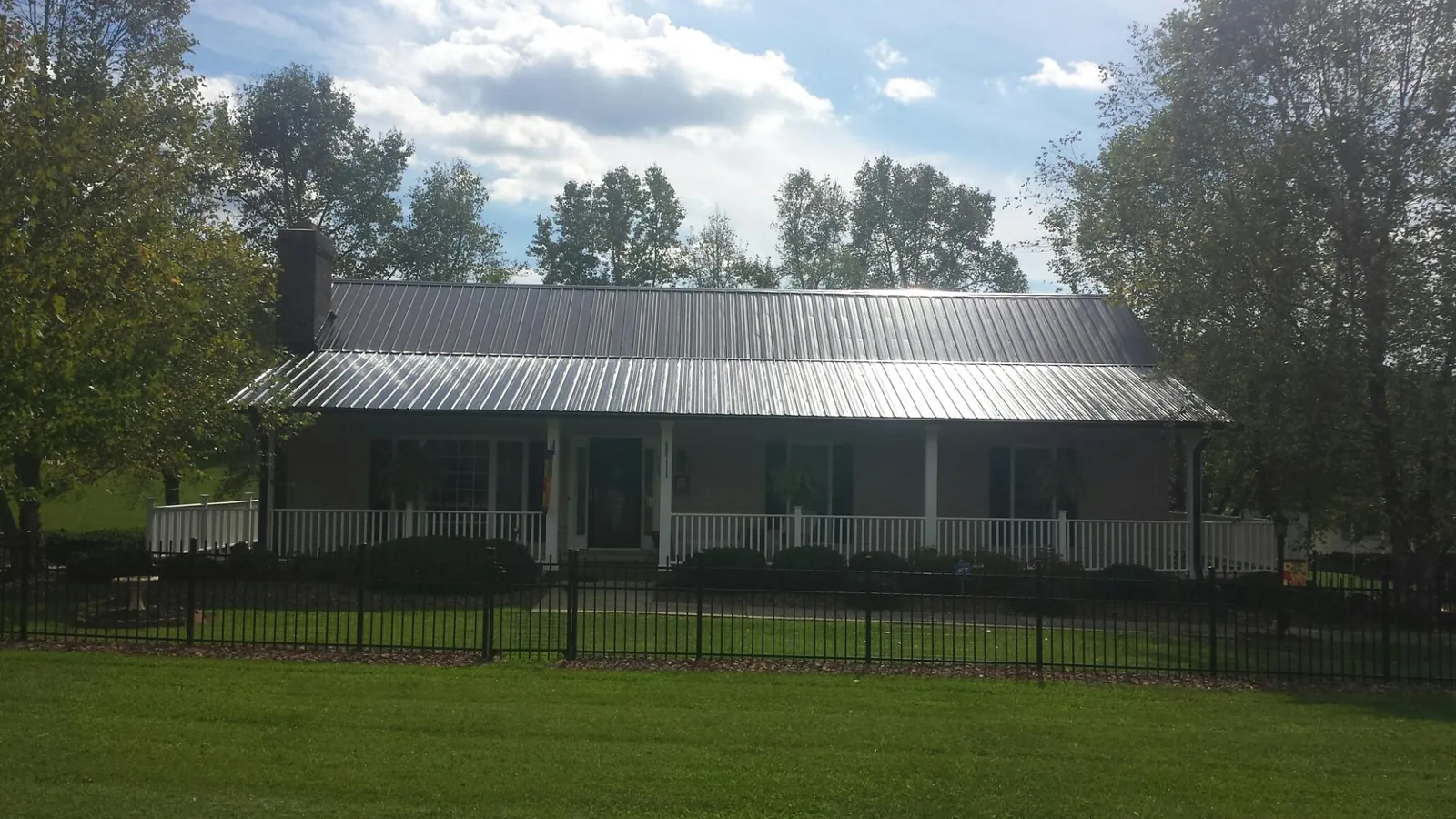 Gray metal roof on a brick ranch with a full width front porch — Gutter Guard Installation work by our crew in Lake Panasoffkee